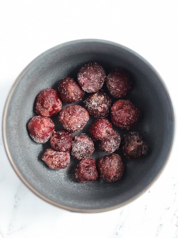 Frozen dark sweet cherries in a small gray bowl.