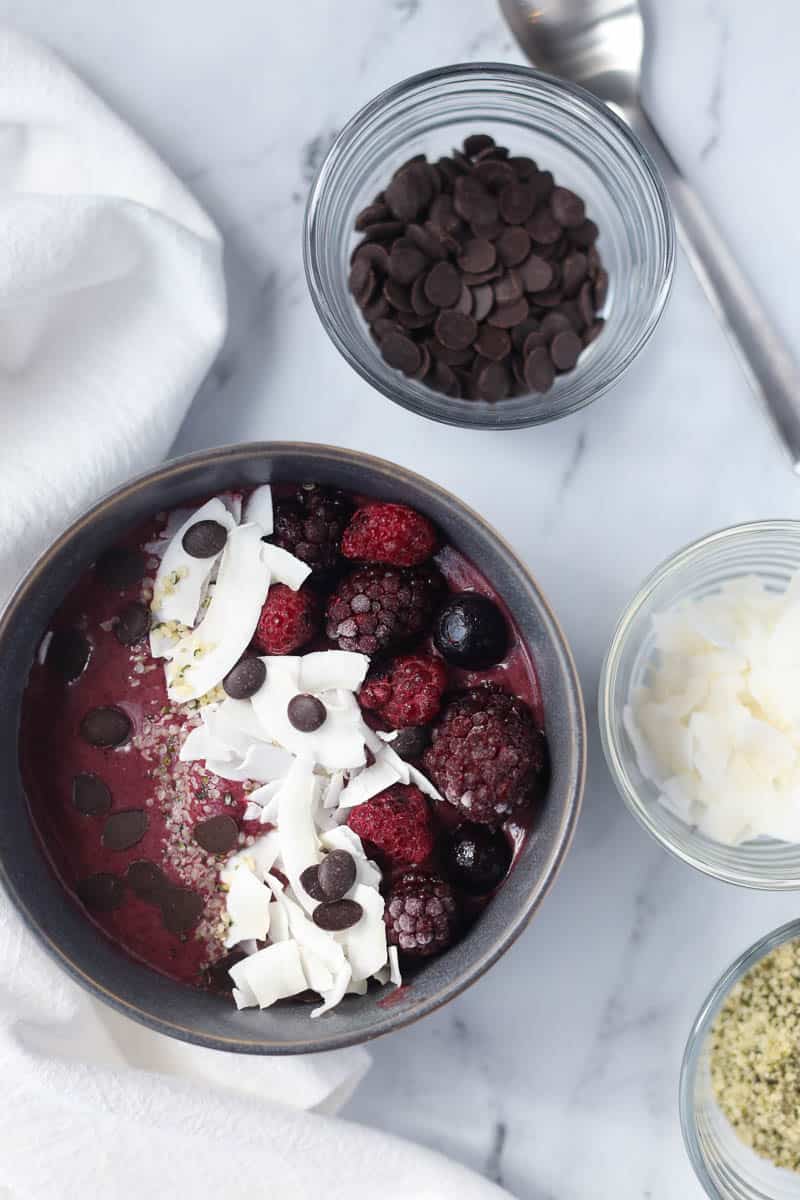 Best smoothie bowl recipe with toppings on white marble countertop.