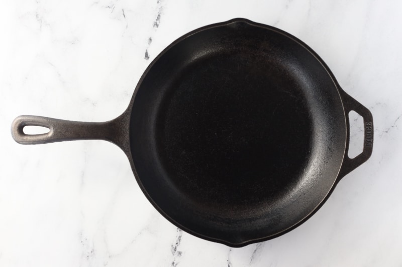 Black cast iron pan on a white marble countertop.