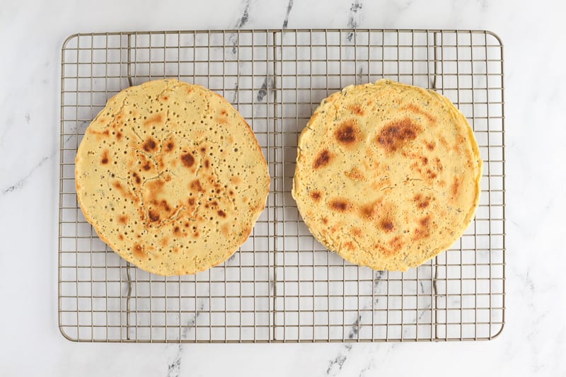 Two cooked gluten-free chickpea flatbreads on a cooling rack.