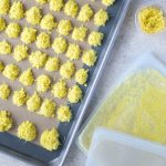 Ginger on a rimmed baking sheet, ginger in a small storage container, and ginger in a freezer-safe bag.