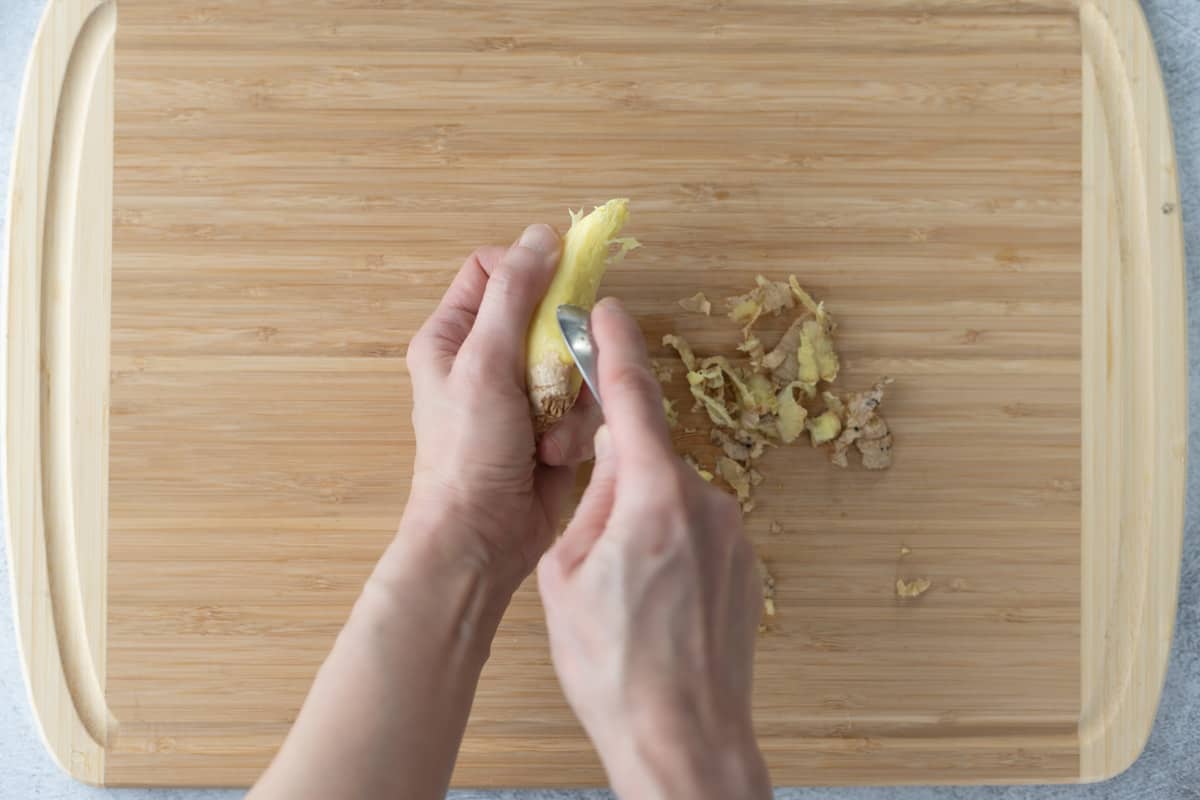 Ginger root being peeled using a spoon.