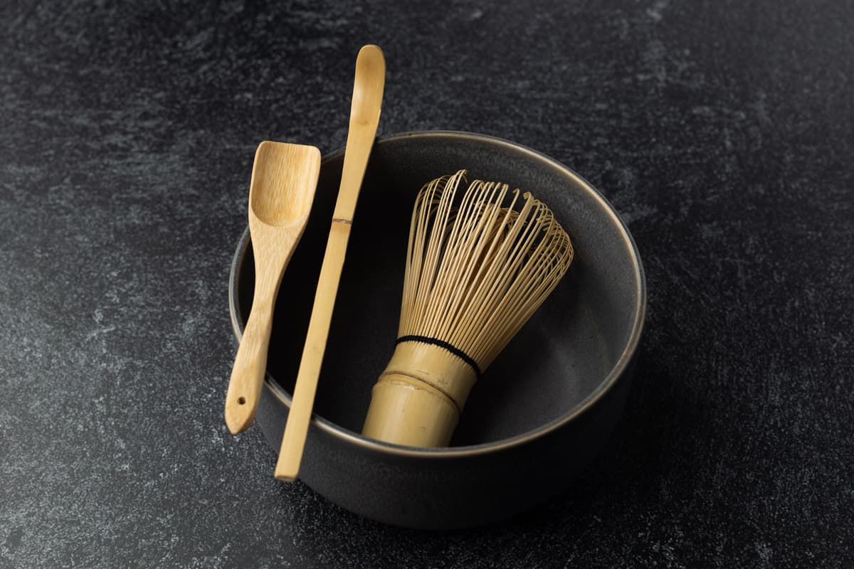 Matcha tea set with bamboo whisk, grey chawan, bamboo scoop, and bamboo spoon.