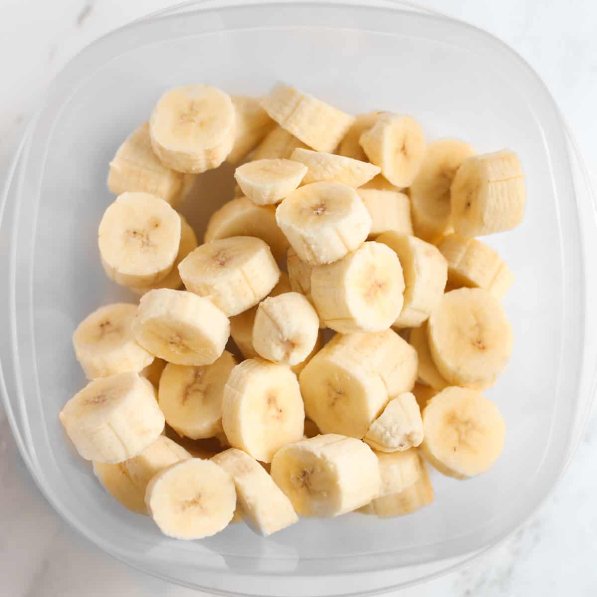 Frozen sliced bananas in a plastic storage container.