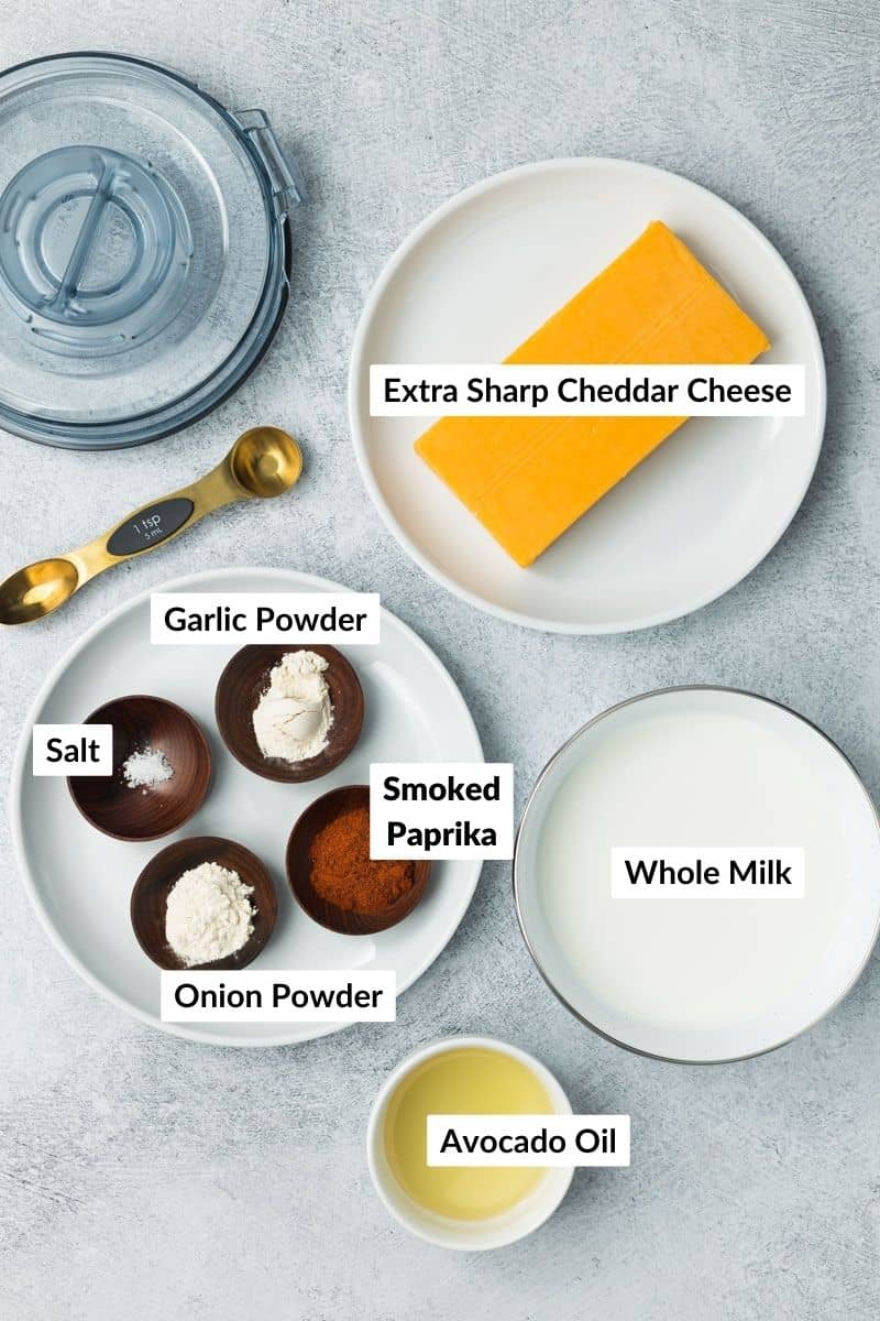 Flourless cheese sauce ingredients arranged in separate containers with labels on a light gray textured background.