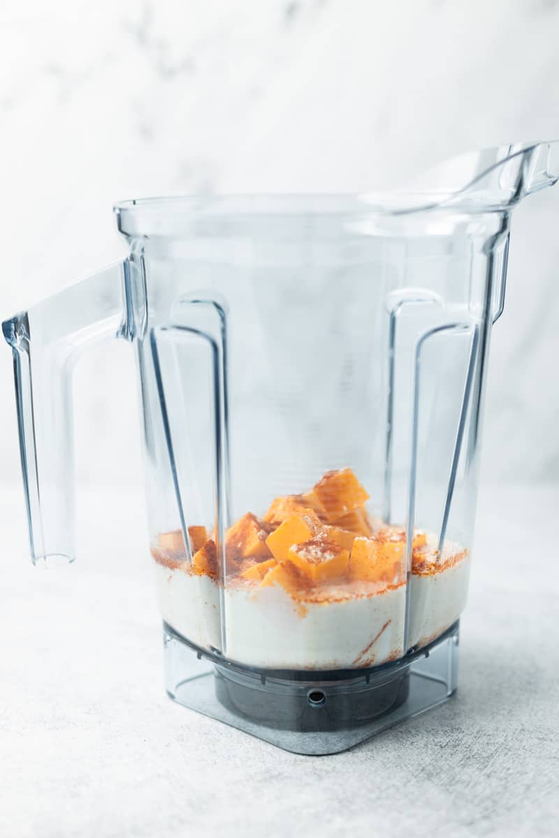 Flourless cheese sauce ingredients loaded in a Vitamix container, vertical view.