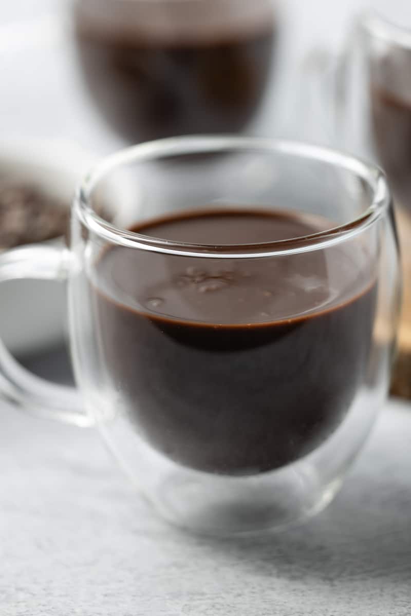 Protein hot chocolate in a double-walled glass mug on a white background.