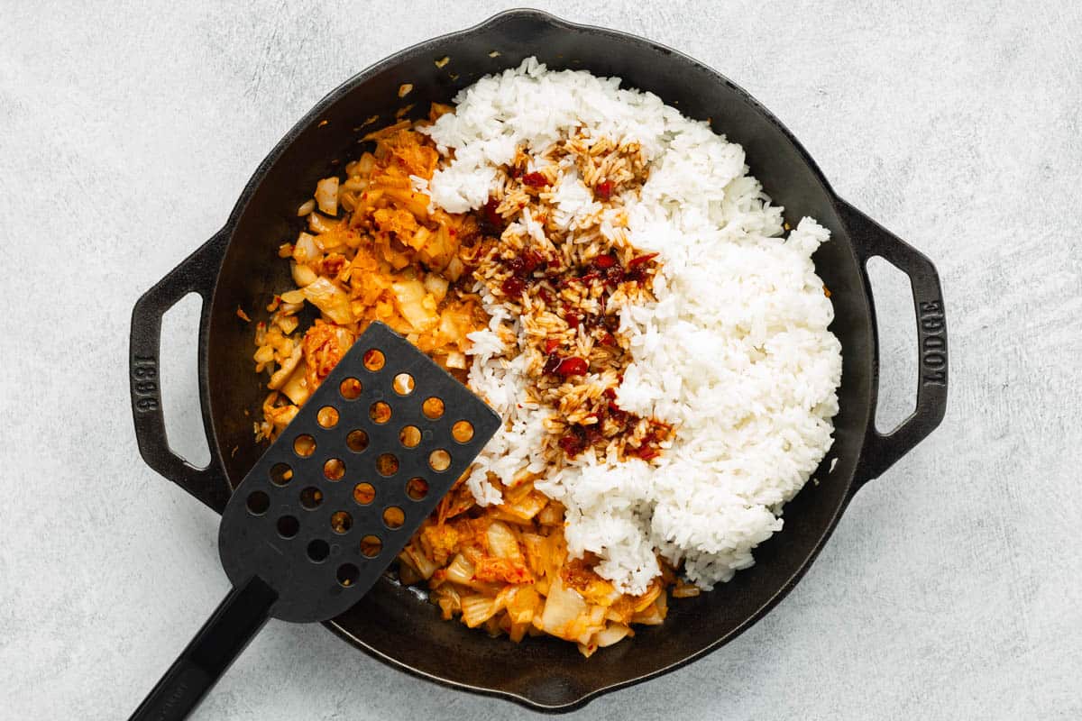 Rice and stir-fry sauce added to the veggies in a cast-iron skillet.