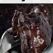 Top-down view of a chocolate protein powder mug cake in a white mug with a fork bite of cake in the foreground.