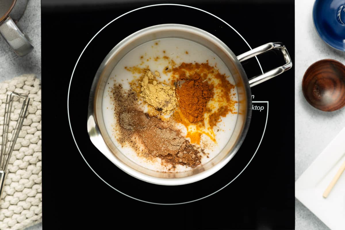 Golden milk ingredients are in a small pot on the stovetop.