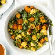 Curry chicken salad with roasted vegetables in a white bowl.