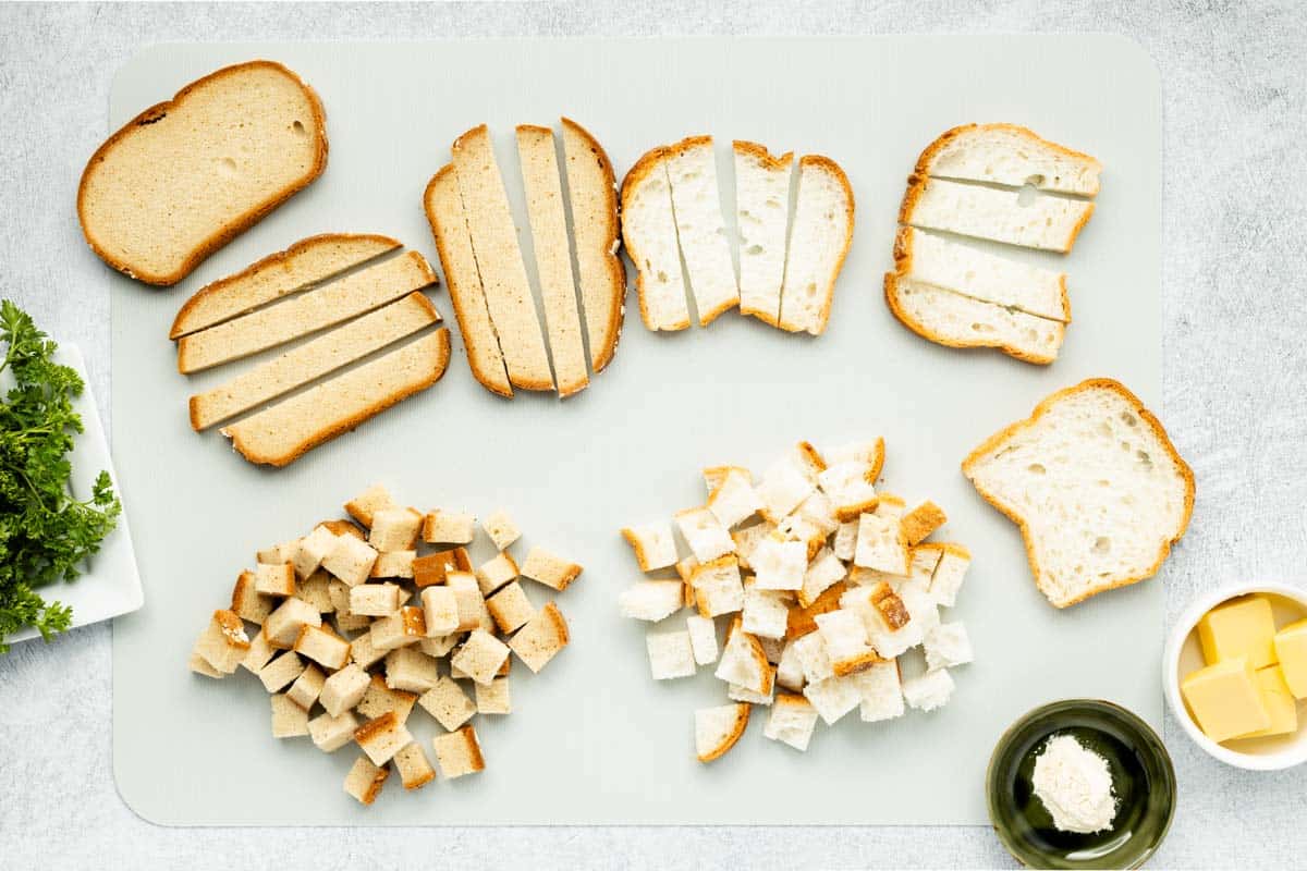 Bread slices cubed on a cutting board.