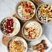 Five bowls of Greek yogurt with different toppings.