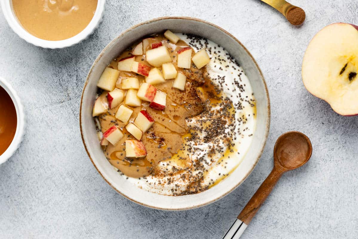 Greek yogurt bowl topped with peanut butter, chopped apple, and honey.