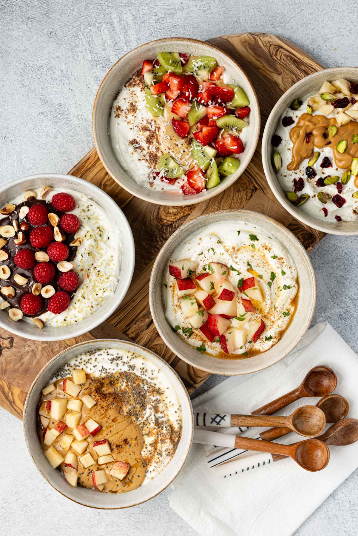 Five bowls of Greek yogurt with different toppings.