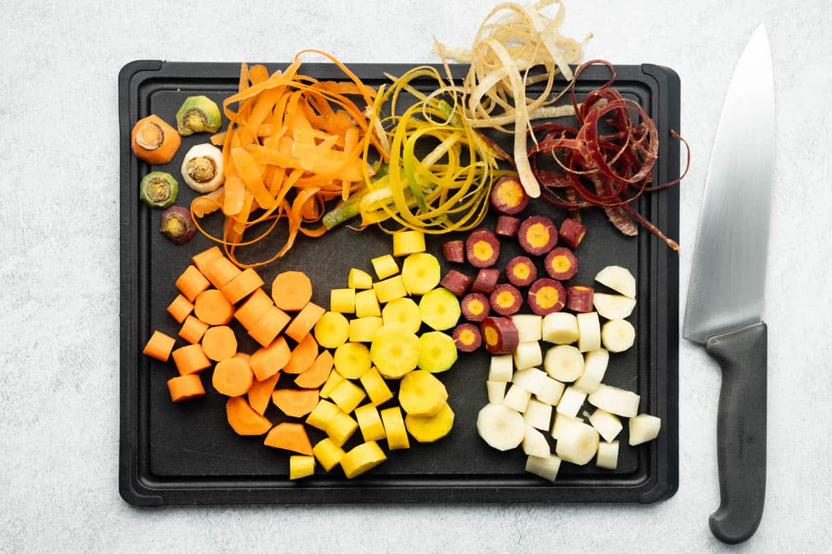 Chopped rainbow carrots on a black cutting board.