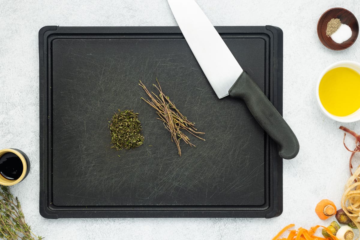 Chopped fresh thyme on a black cutting board.