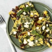 Five slices of sheet pan eggs on a green plate with fork.