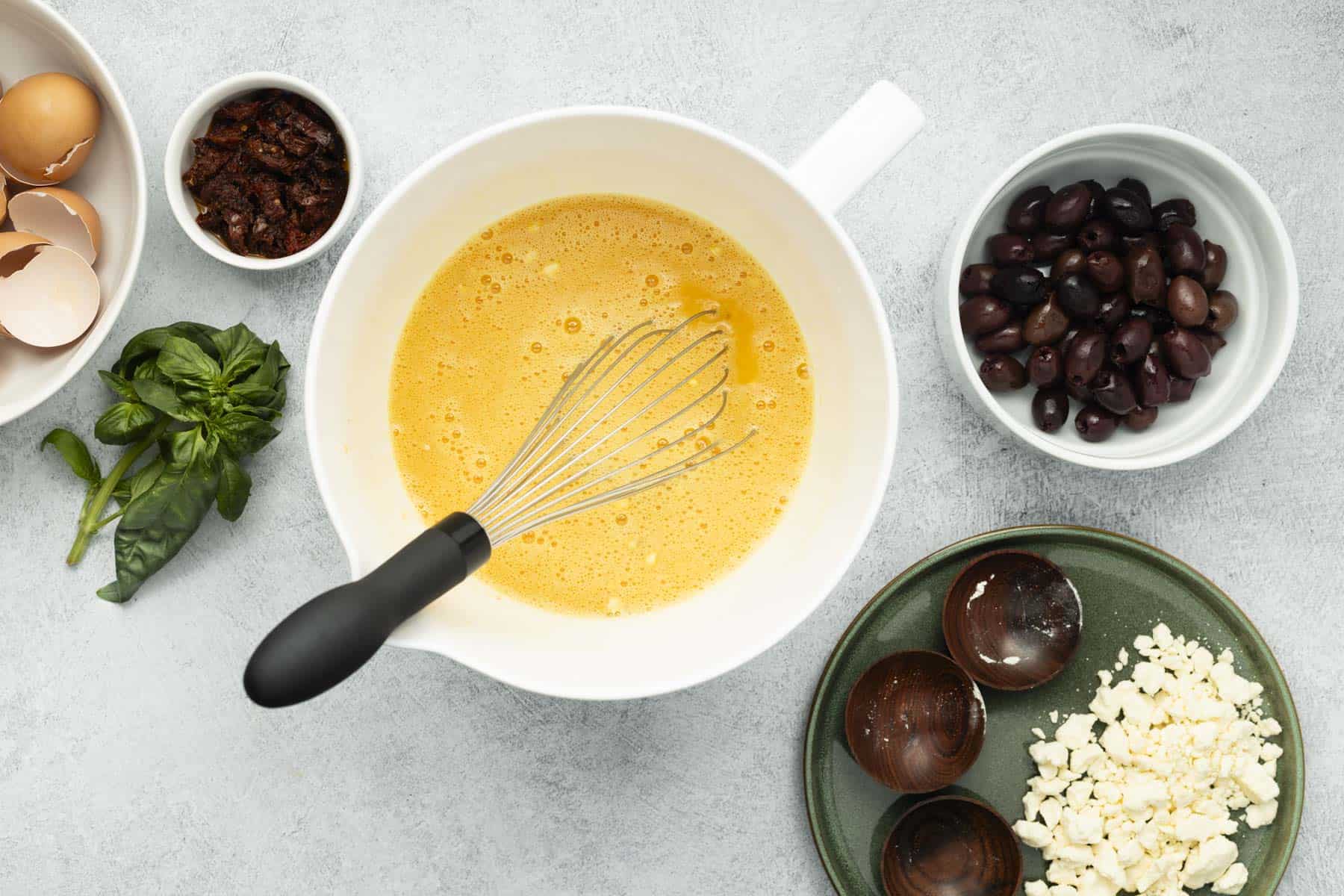 Cracked eggs in a white bowl with seasonings whisked together.