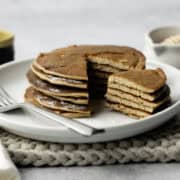 Stack of pancakes on a white plate with fork.