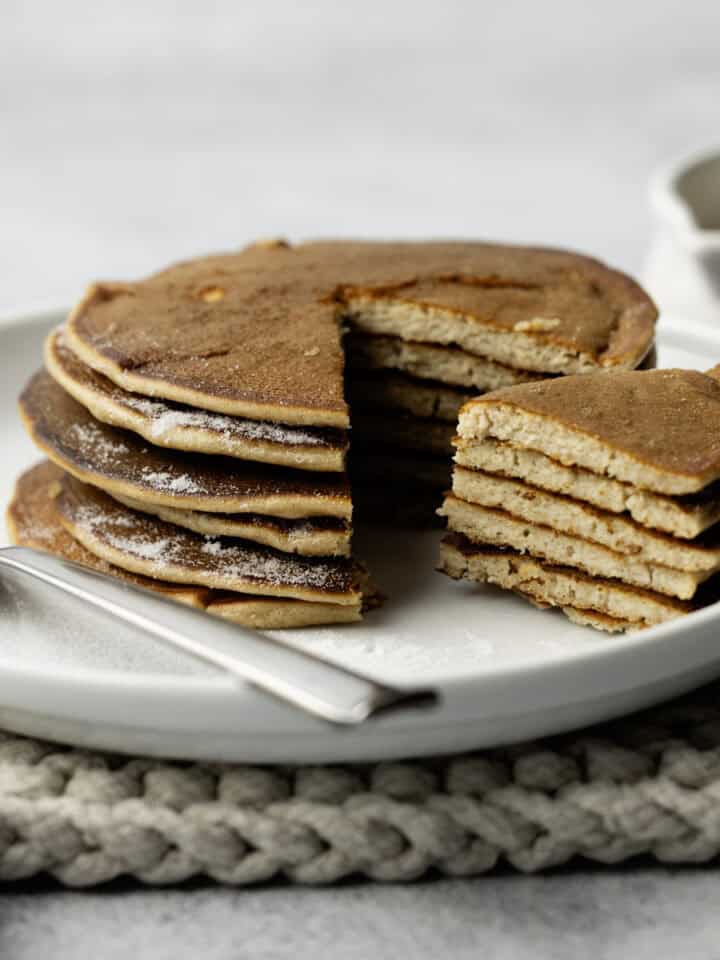 Stack of pancakes on a white plate with fork.
