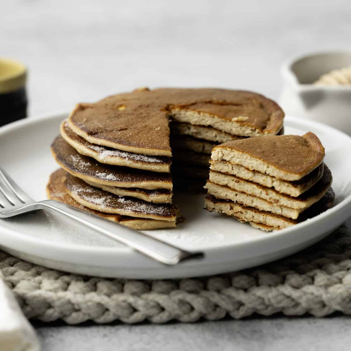 Stack of pancakes on a white plate with fork.