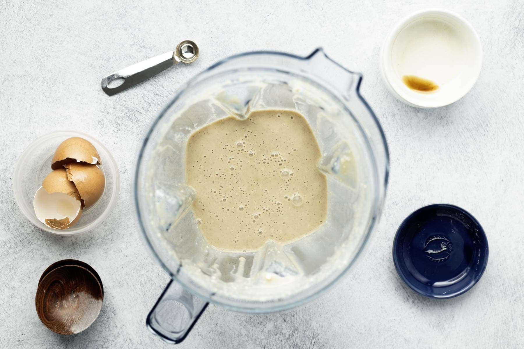 Blended pancake batter in a clear plastic pitcher.